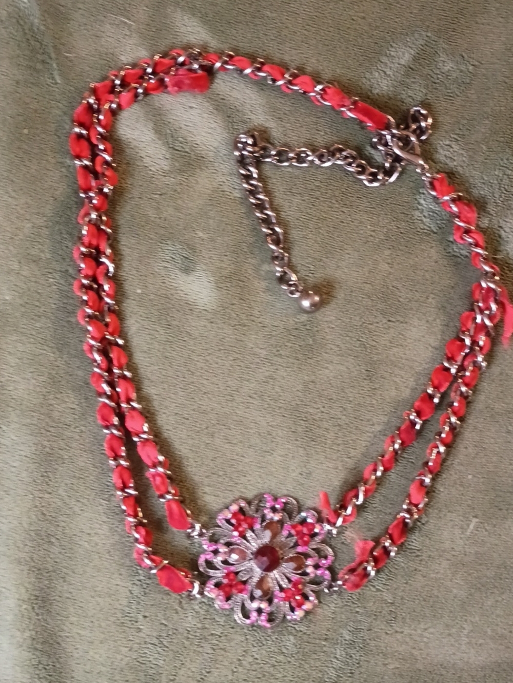 Multi Strand Necklace Featuring Interwoven Ribbon Centered Around Ornate Floral